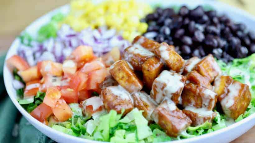 chopped salad topped with bbq tofu, corn, black beans tomatoes and red onion