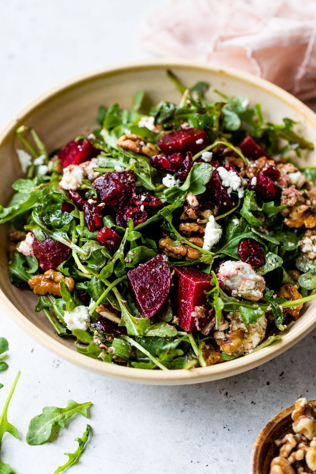 Arugula beet salad with goat cheese and walnuts in a bowl.