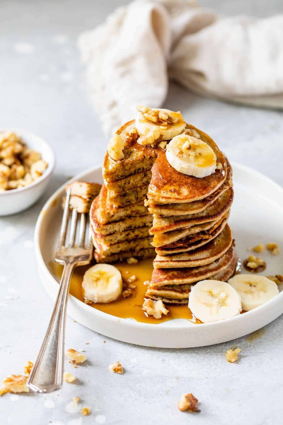 serving of banana oatmeal pancakes served with banana slices and chopped walnuts