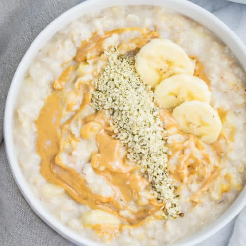 bowl of oatmeal topped with bananas, peanut butter and hemp seeds