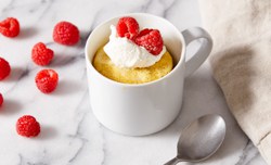 vanilla mug cake topped with cream and berries
