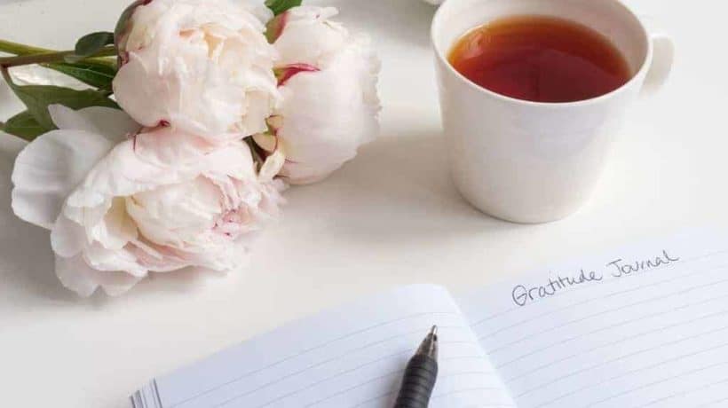 a journal, flowers, and tea on a desk