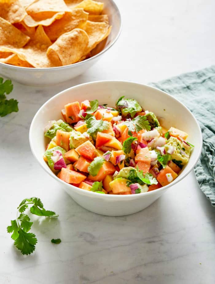 papaya avocado salsa with cilantro and red onion in a white bowl