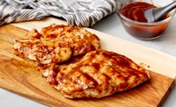 grilled chicken breast on wood cutting board