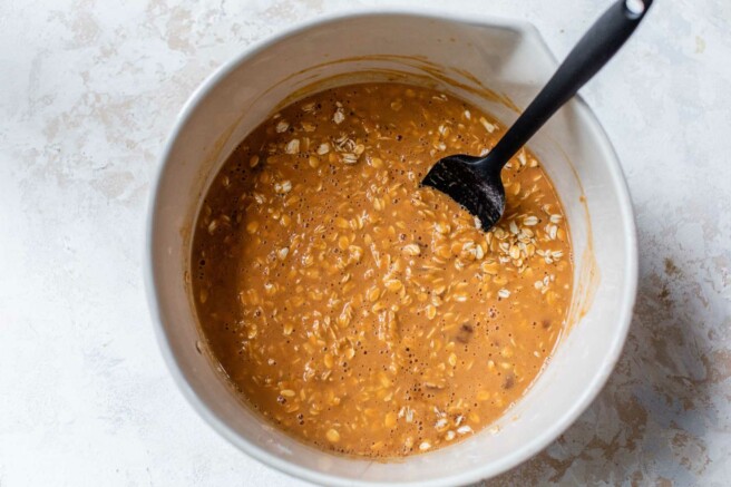 Combining oats with pumpkin mixture in a large bowl.