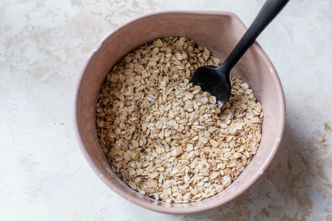 Mixing oats with cinnamon in a large bowl.