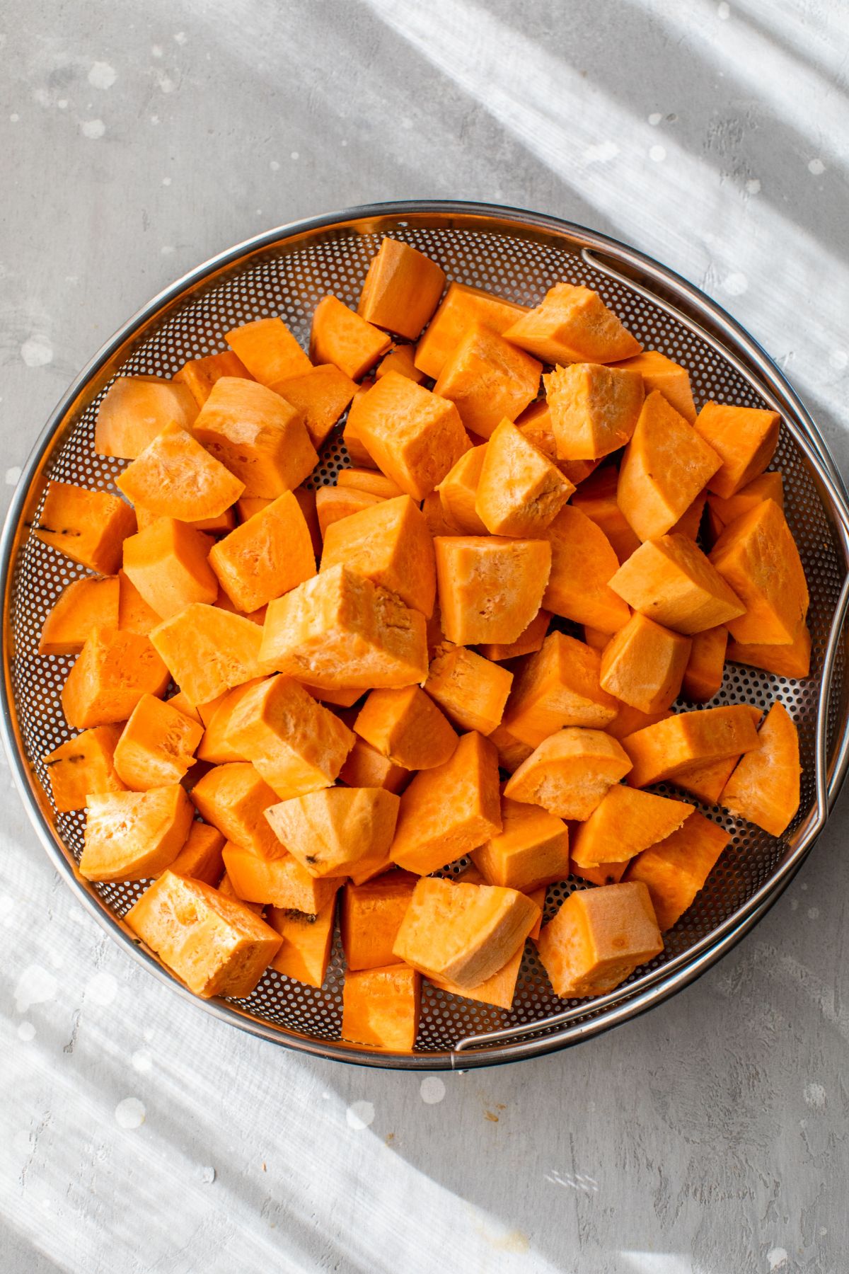 Chopped sweet potato in a colander.