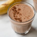 banana pbfit chocolate protein shake in a glass next to a banana