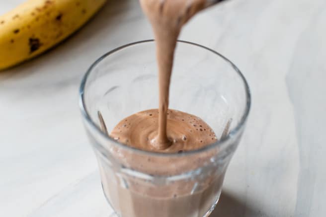 banana peanut butter smoothie being poured into a glass