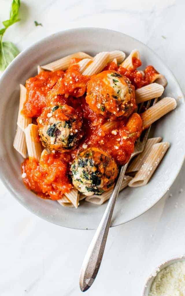 turkey spinach meatballs served over pasta in a bowl