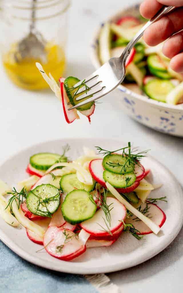 using a fork to get a bite of radish and cucumber salad