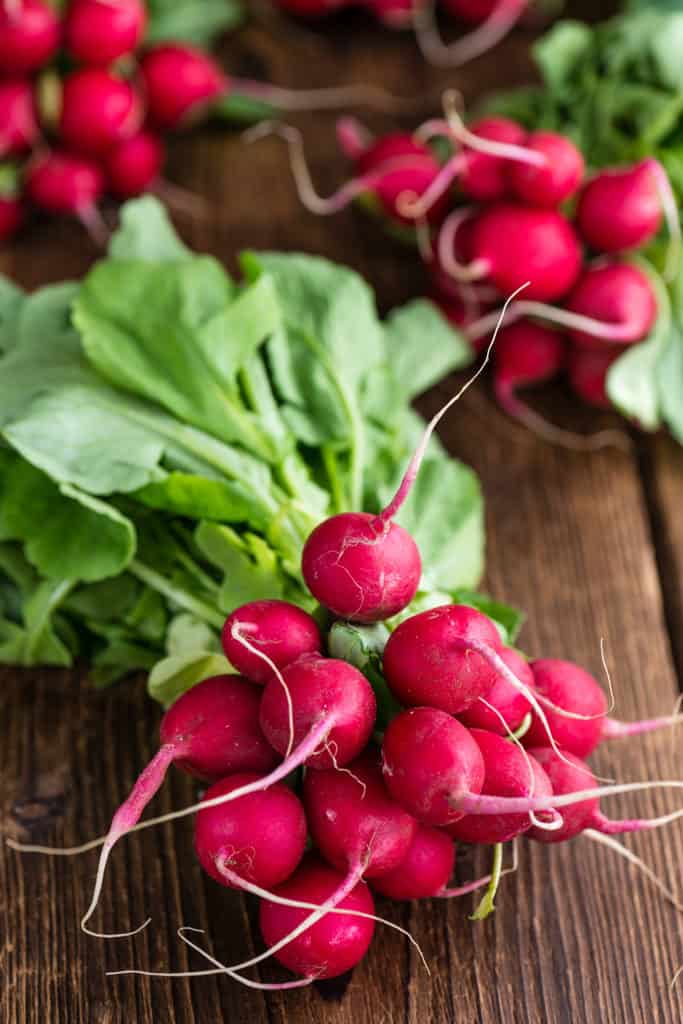 a bunch of radishes on wood cutting board