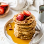 healthy oatmeal pancakes on white plate topped with strawberries