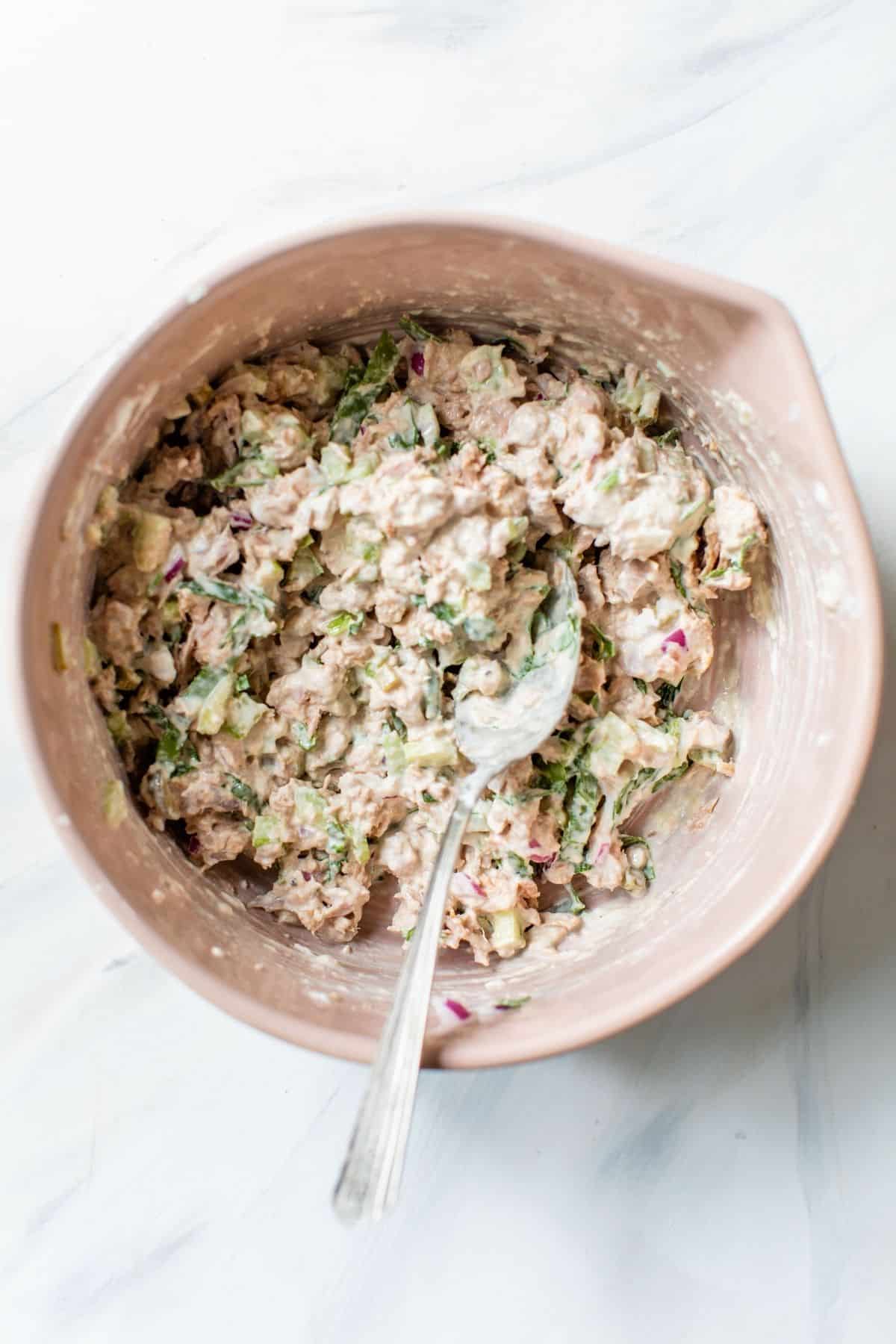 ingredients for tuna salad recipe stirred in a large mixing bowl