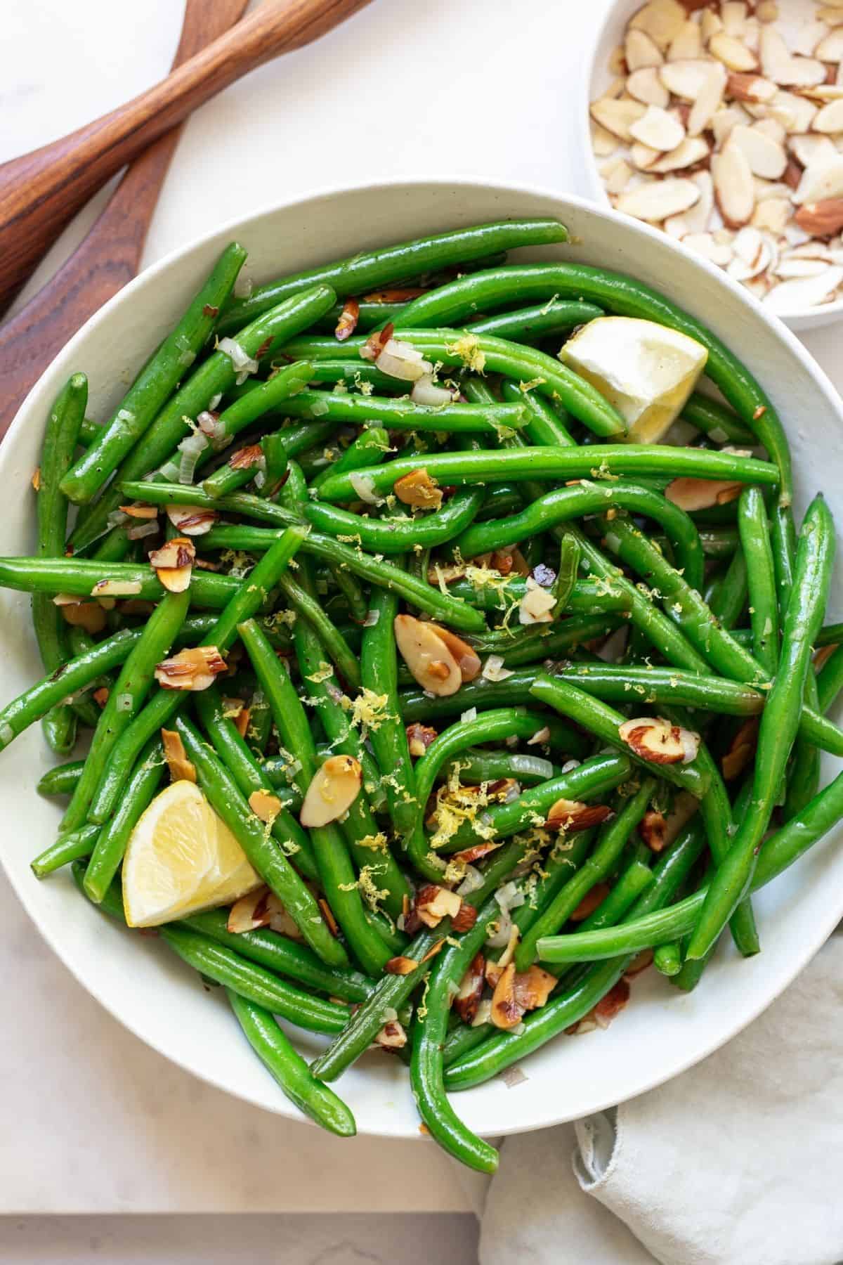 green beans almandine in a large white serving bowl