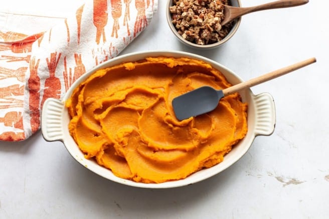 spreading mashed sweet potatoes into a casserole dish