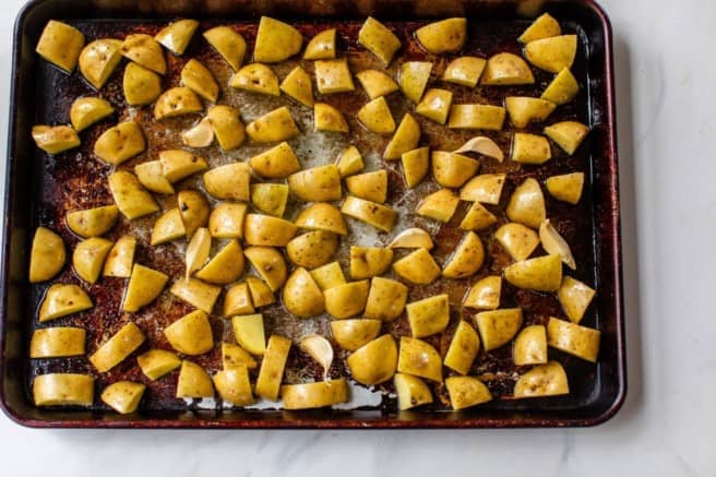 placing potatoes on a baking sheet for roasting