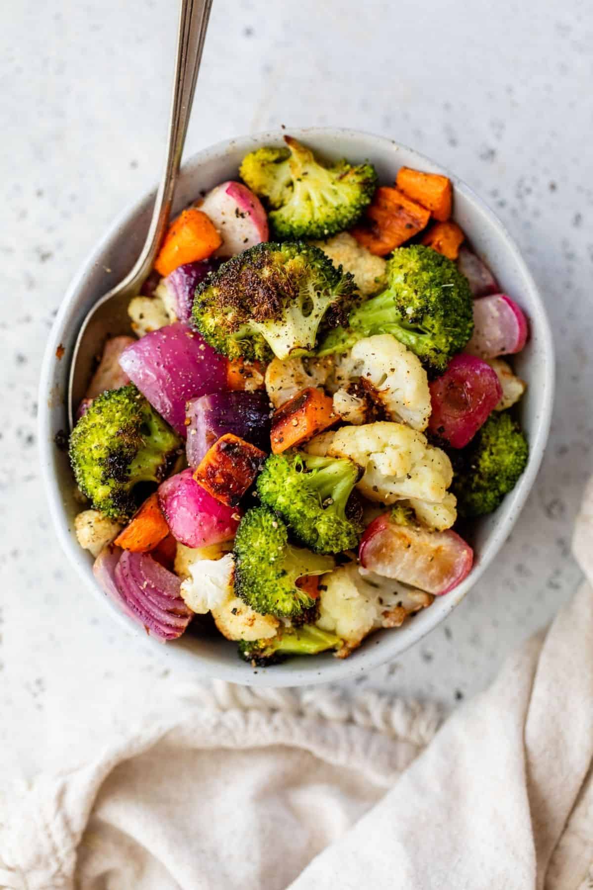 roasted vegetables served in a white bowl with a fork