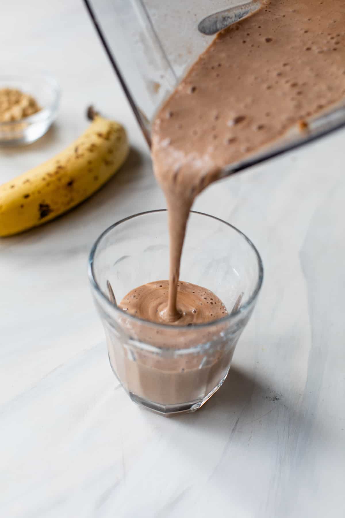 banana pb fit chocolate shaking pouring from the blender into a glass