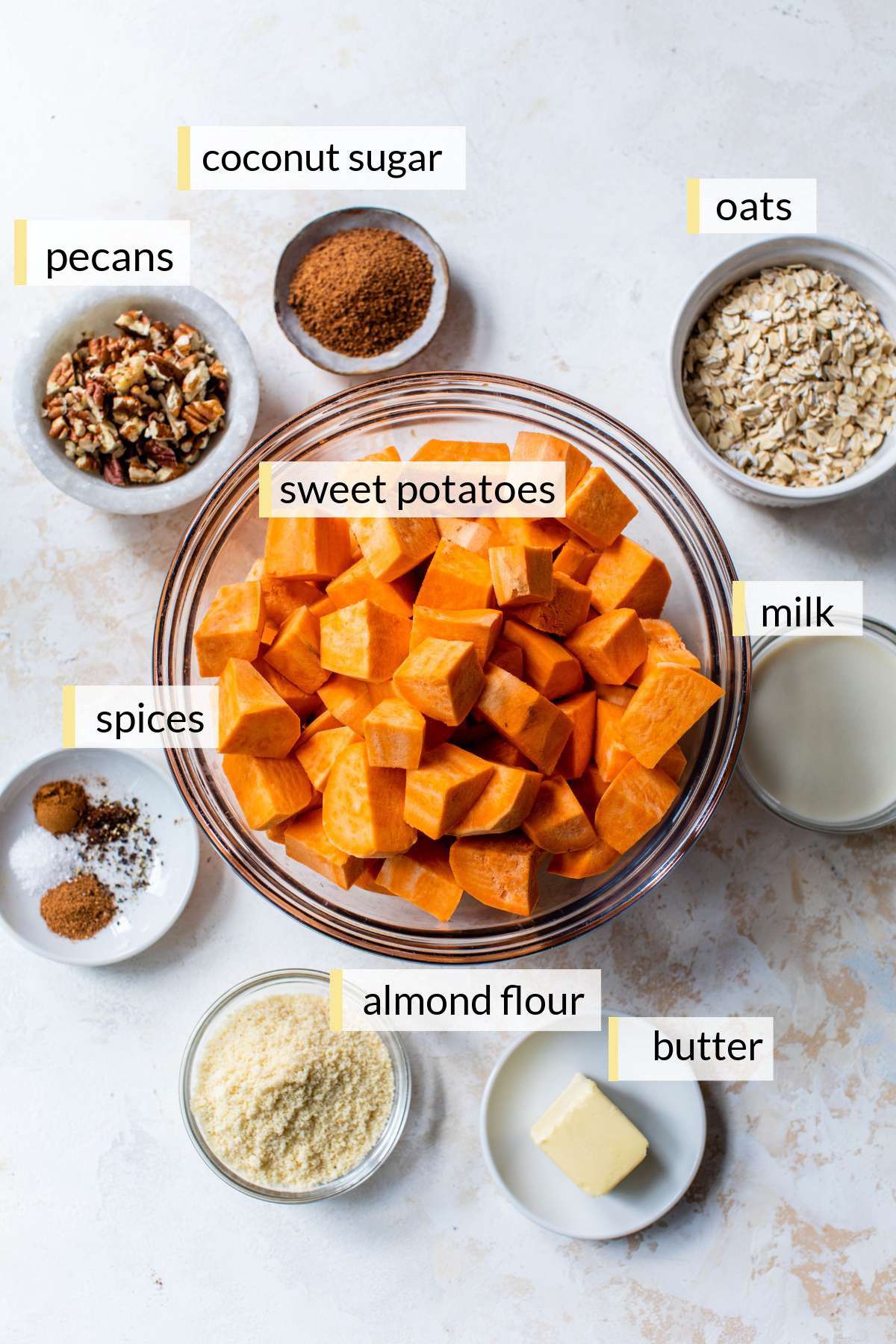 Chopped sweet potatoes, oats, pecans, butter, milk and spices divided into small bowls.