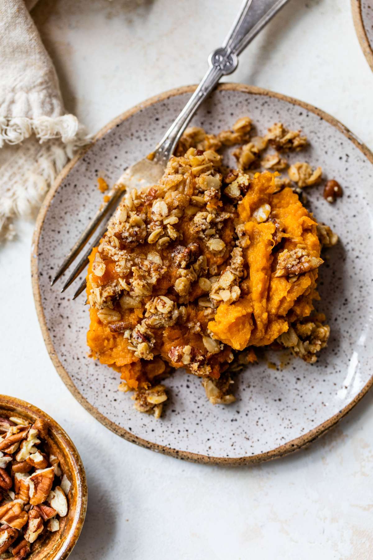 A serving of sweet potato casserole on a plate with a fork.