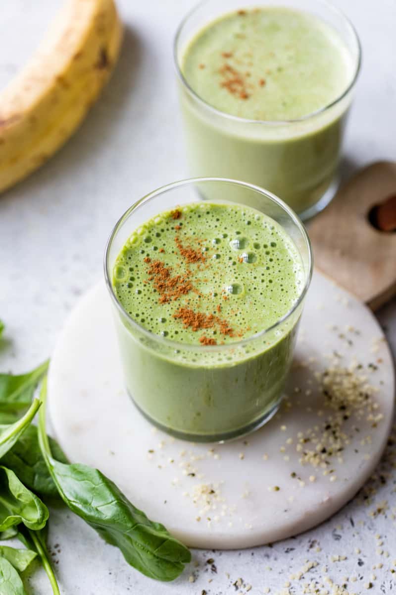 two green breakfast smoothies topped with cinnamon