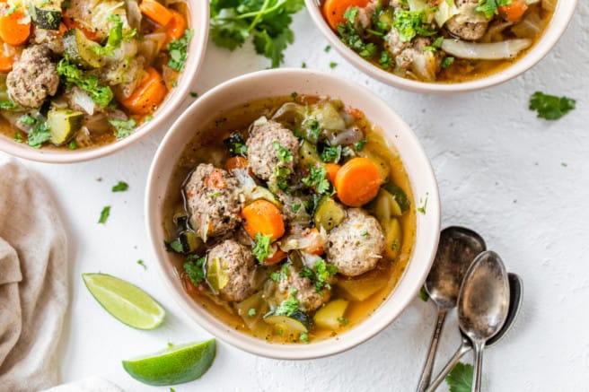 meatball soup in bowl topped with cilantro and lime