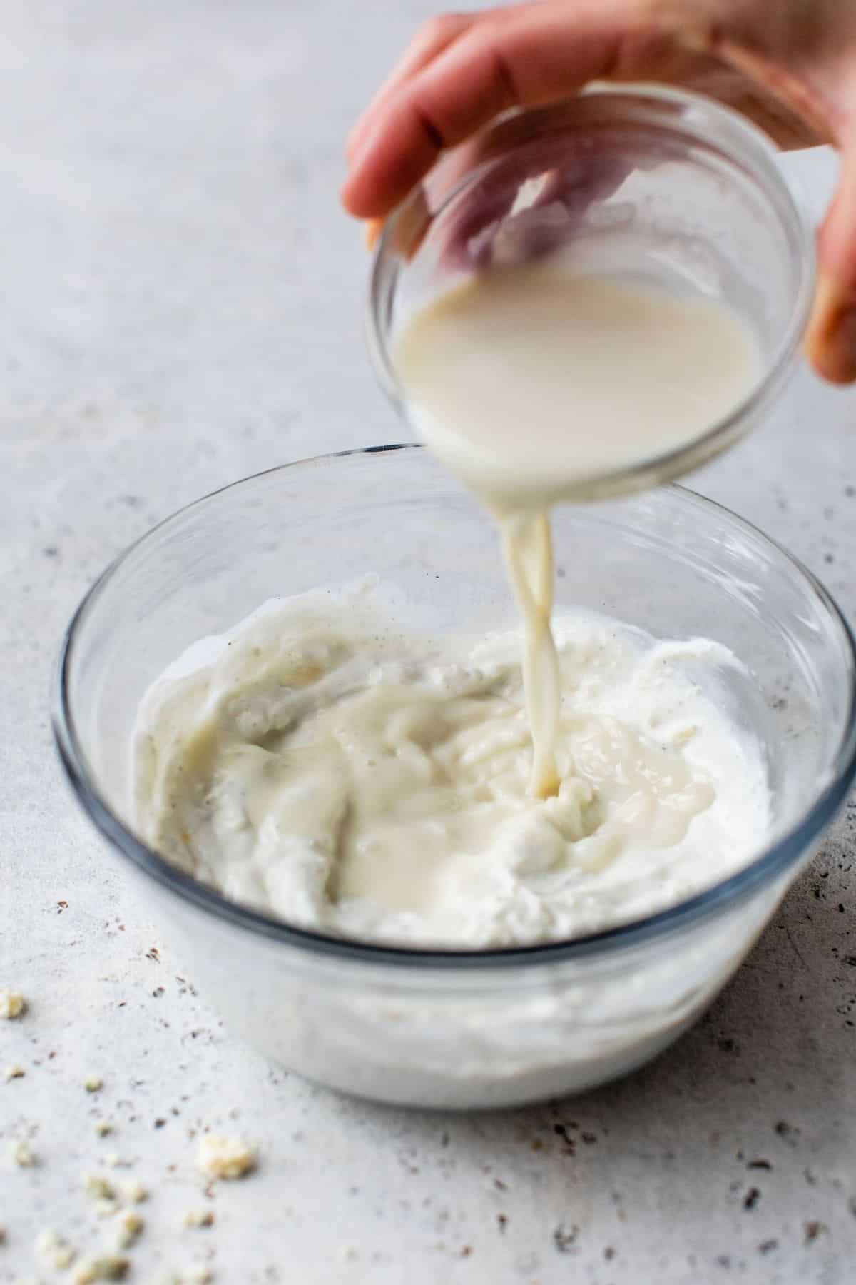 pouring milk into Greek yogurt mixture