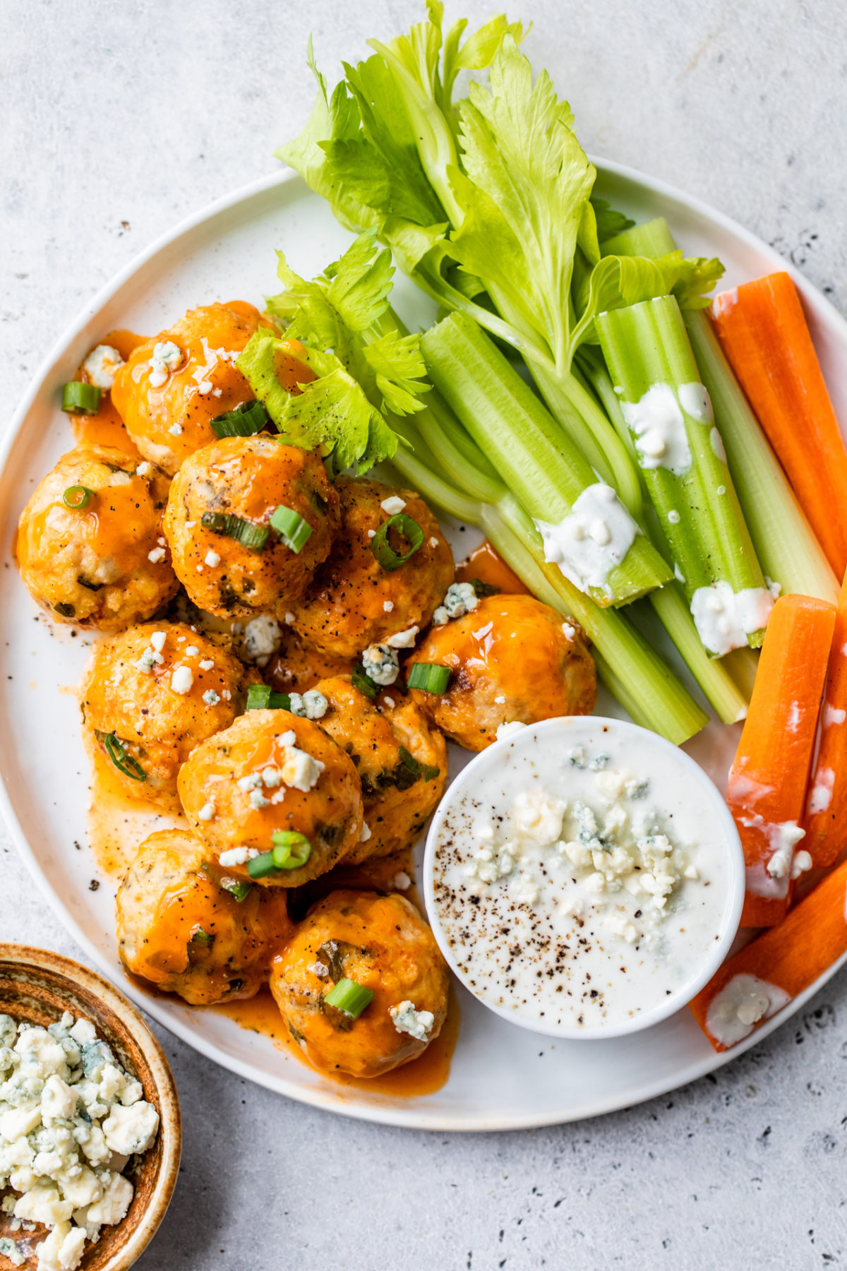 slow cooker buffalo chicken meatballs on white plate with celery and carrots