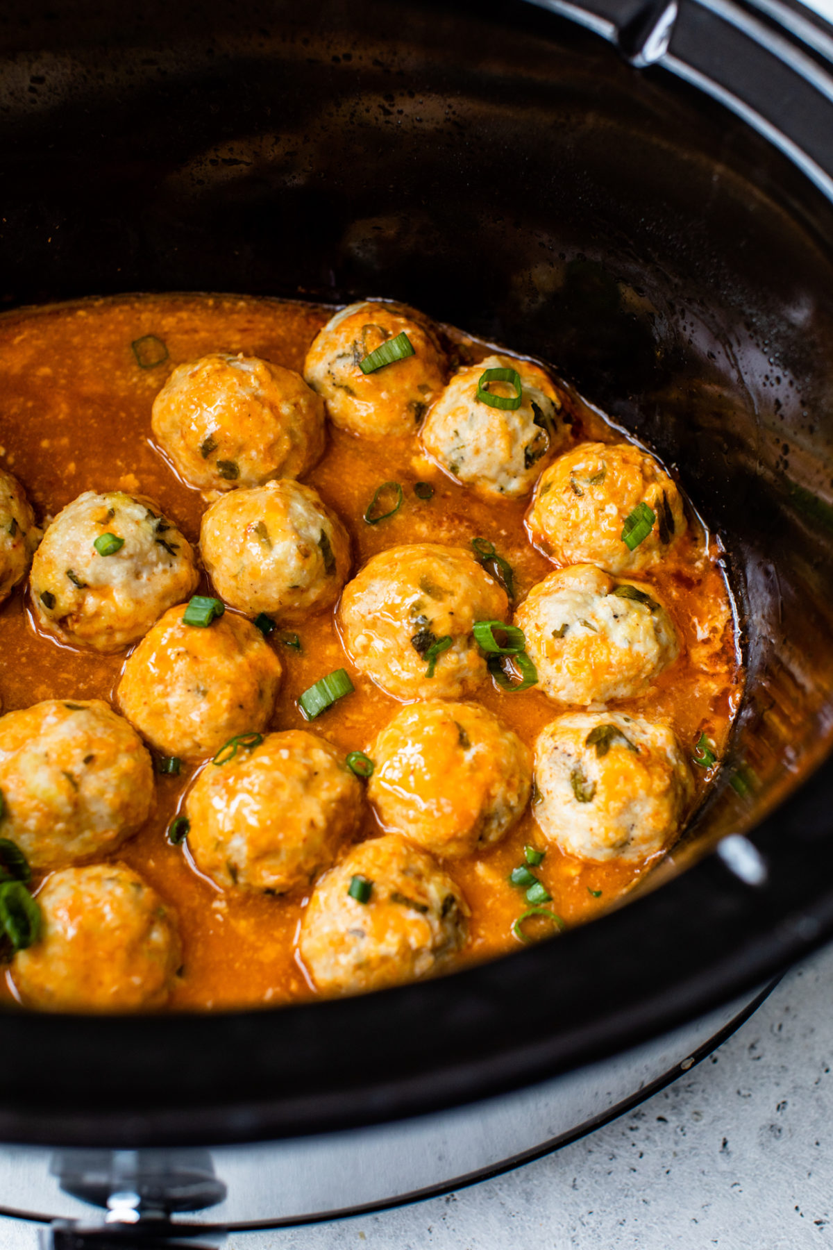 chicken meatballs covered in buffalo sauce in the slow cooker