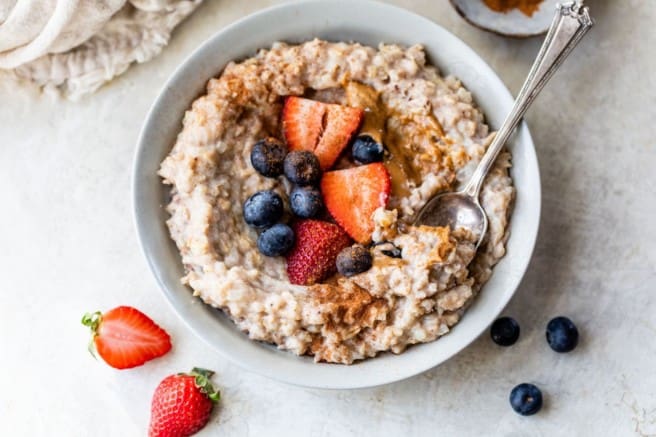 cauliflower oatmeal in a bowl topped with berries and cinnamon