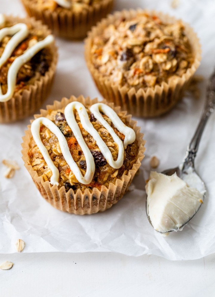 Carrot cake baked oatmeal cups topped with a drizzle of cream cheese icing.