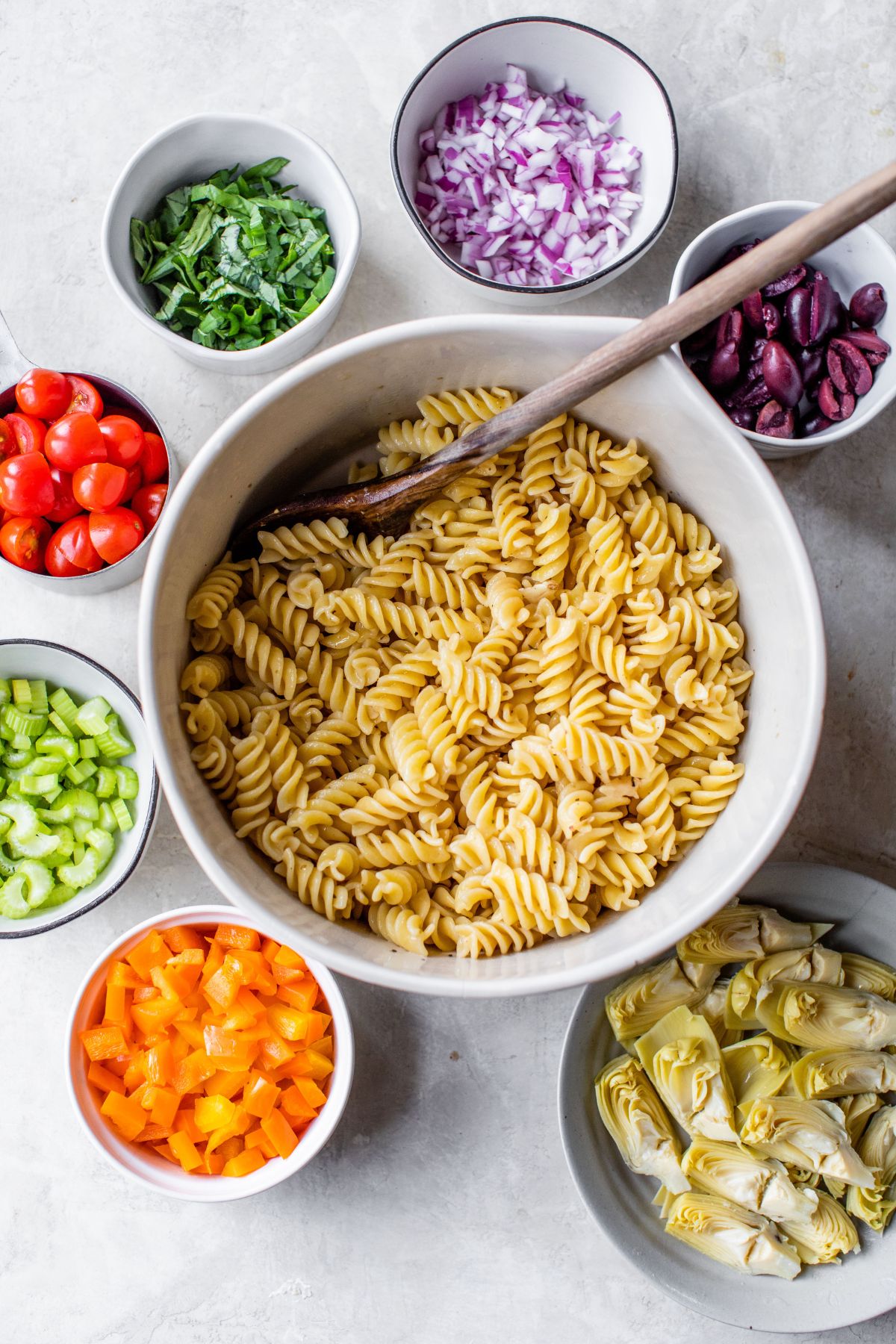 Ingredients for pasta salad divided into separate bowls.