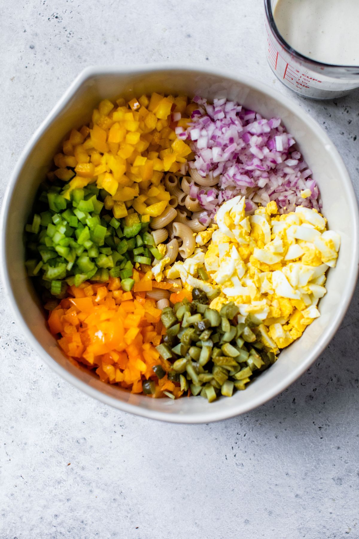 Combining macaroni with veggies in a large bowl.