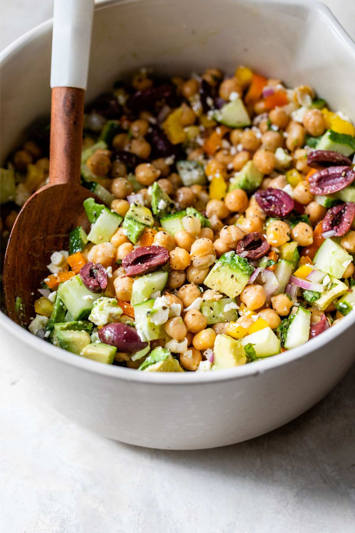 chickpea salad in a bowl with wooden spoon