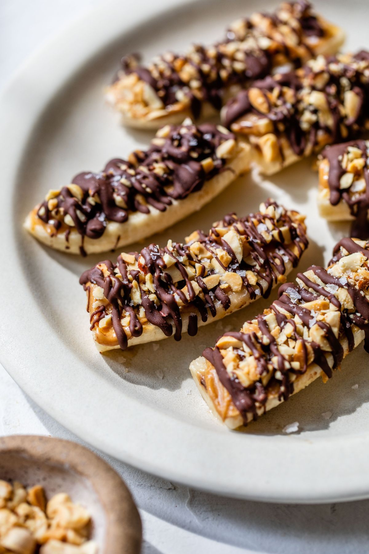 Chocolate covered bananas on a white plate.