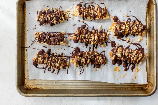 Drizzling chocolate over peanut butter covered bananas.