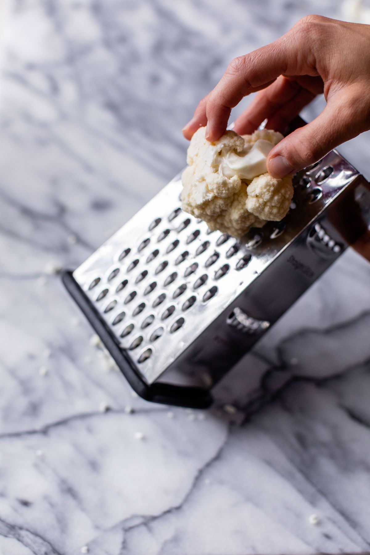 Using a box grater to grate cauliflower.