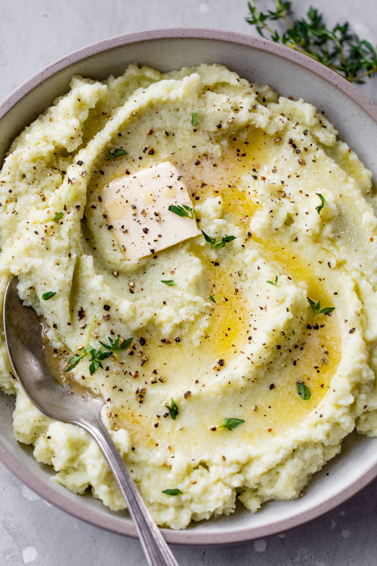 Mashed cauliflower in a bowl with a large serving spoon.