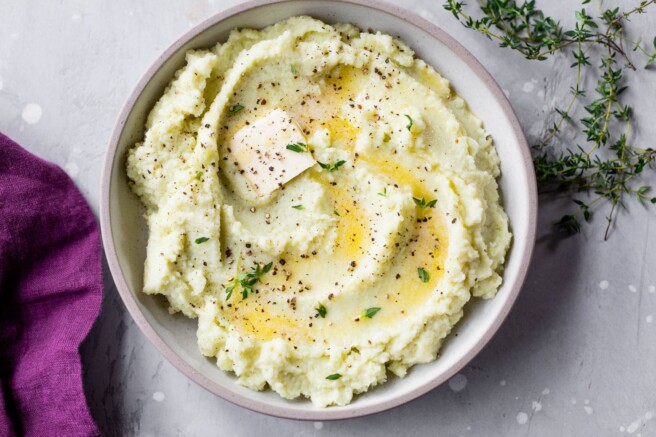 Cauliflower mash in a bowl with butter and thyme.