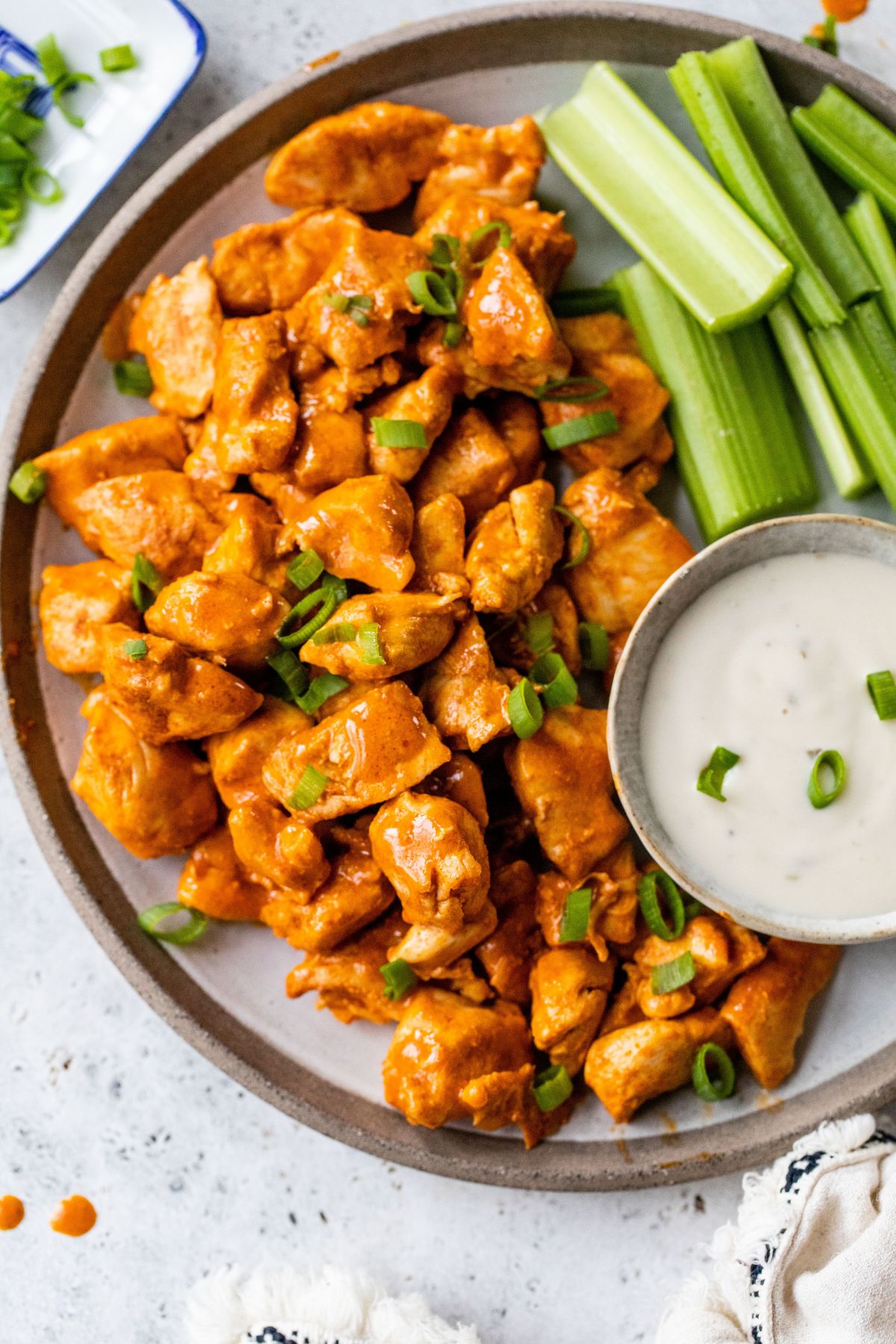 Buffalo chicken bites on a plate with celery sticks and dressing.