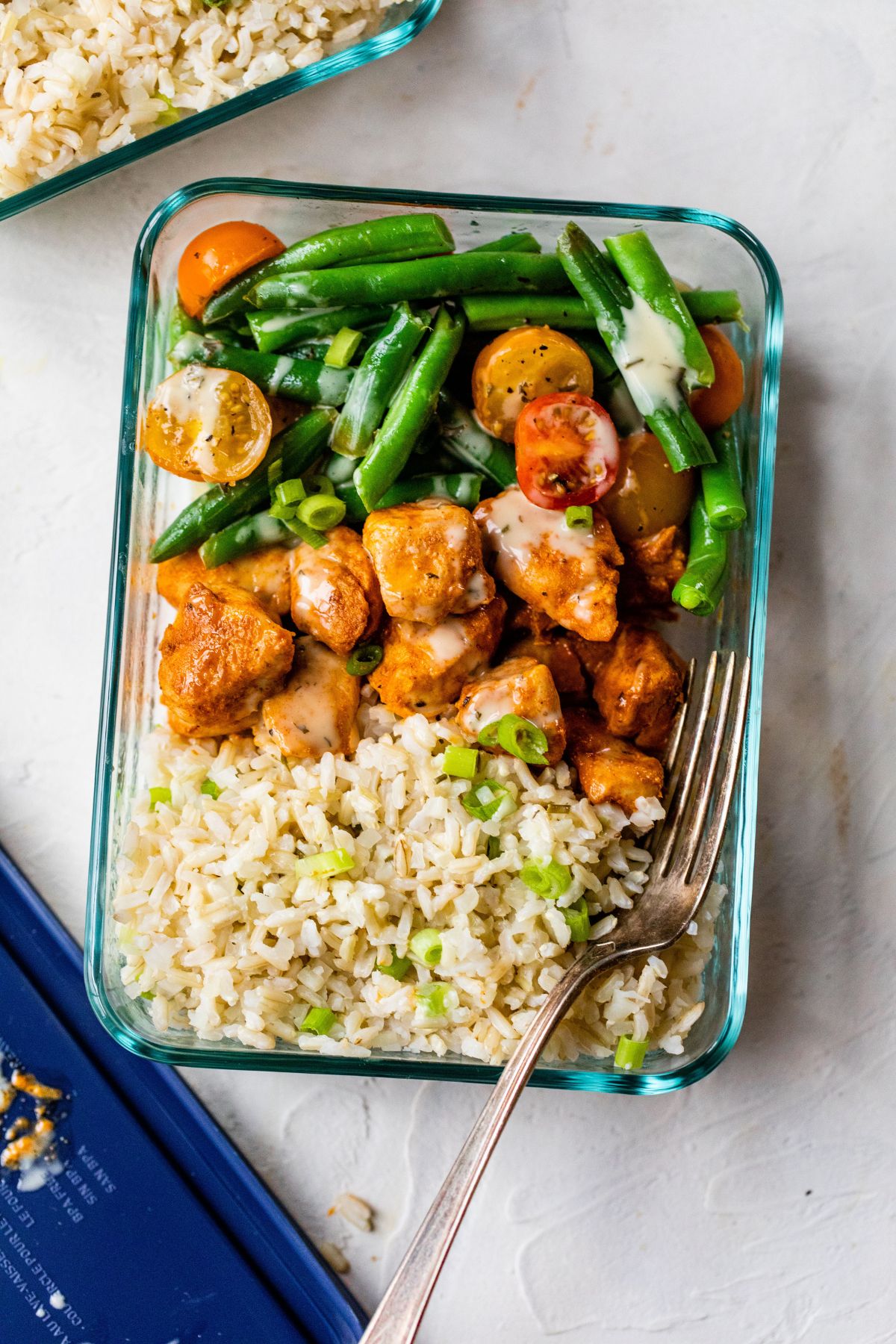 Glass container with chicken, rice and green beans.