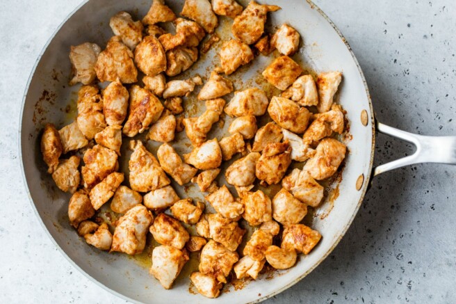 Cooking chunks of chicken in a skillet.