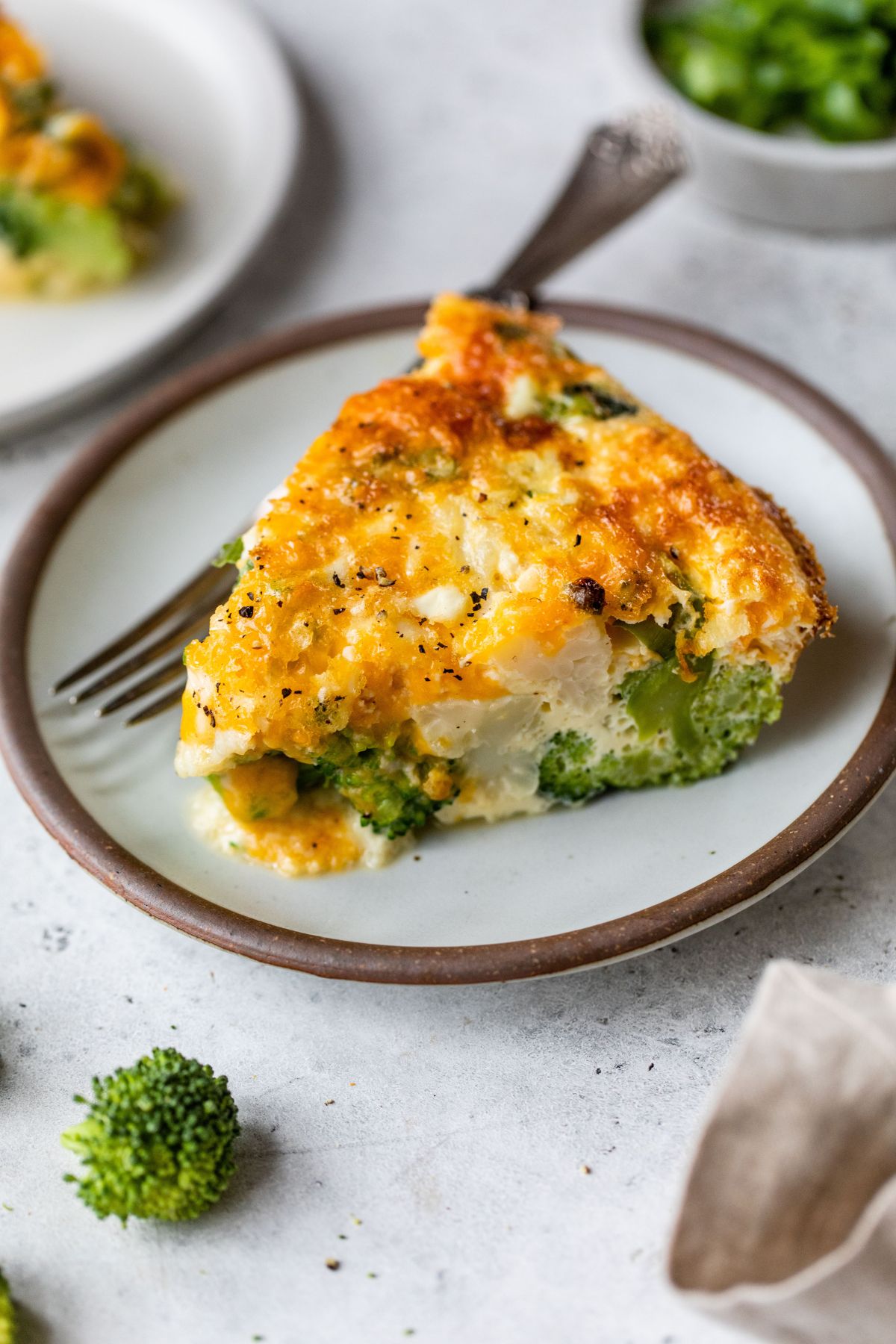 Serving of crustless quiche with broccoli on a plate.