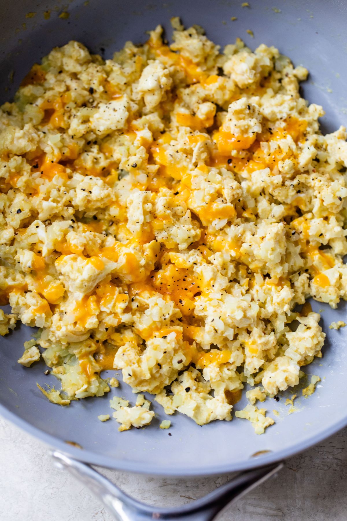 Cauliflower eggs topped with cheese in a skillet.