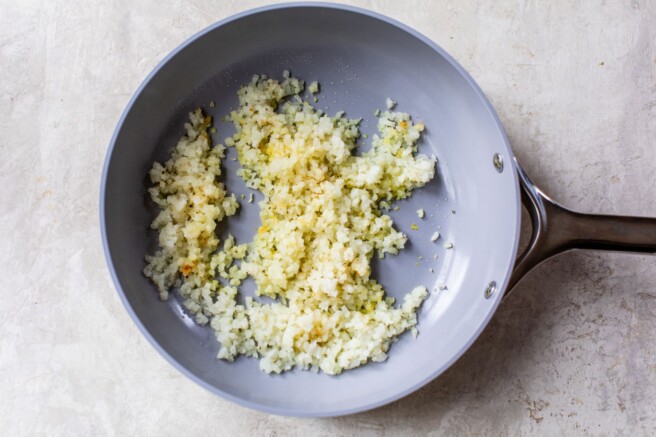 Cooking riced cauliflower in a skillet.