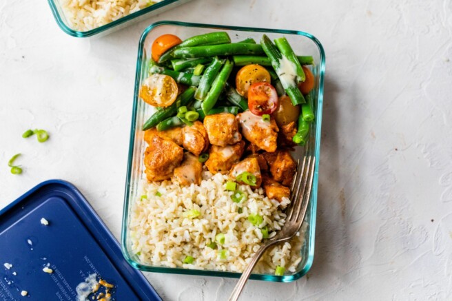 Glass container with chicken, rice and green beans.