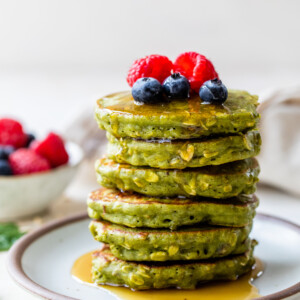 Stack of healthy spinach pancakes topped with oats and berries
