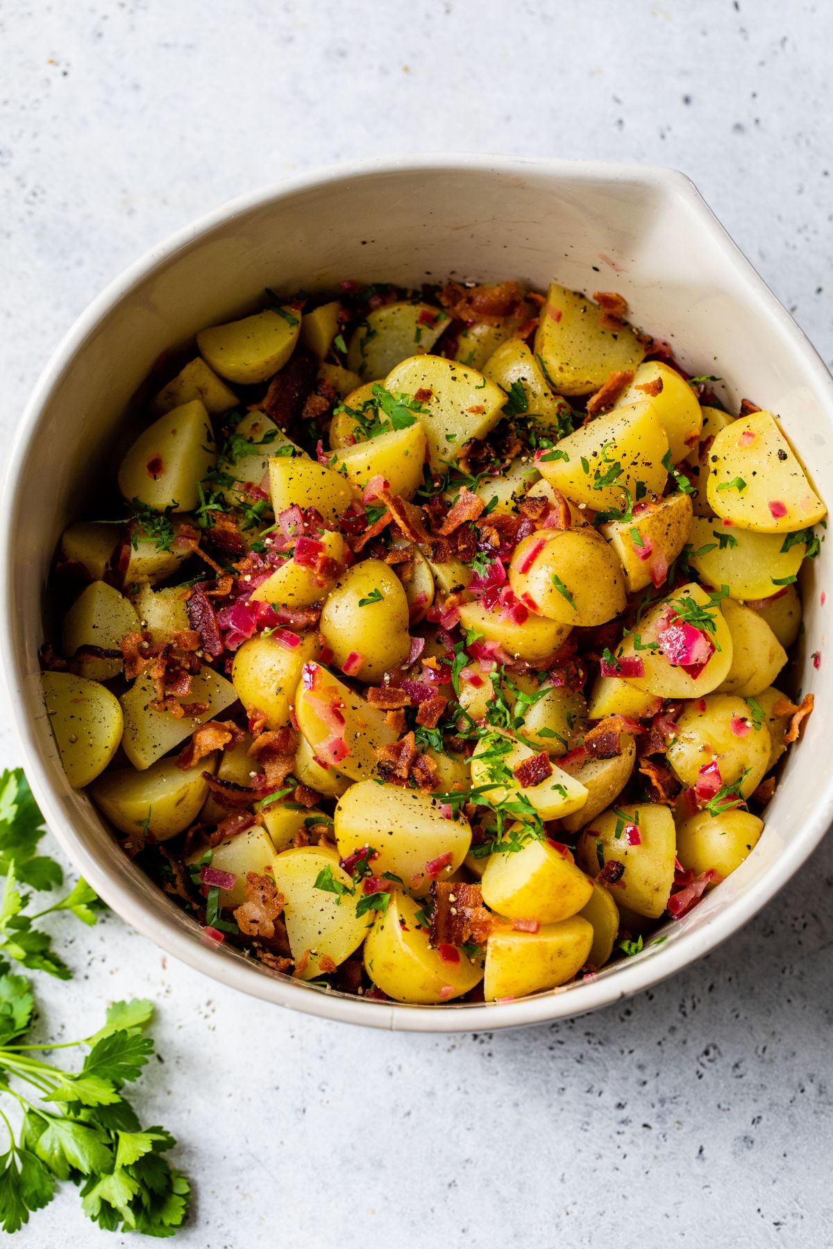 Tossing potatoes with dressing, bacon and parsley.