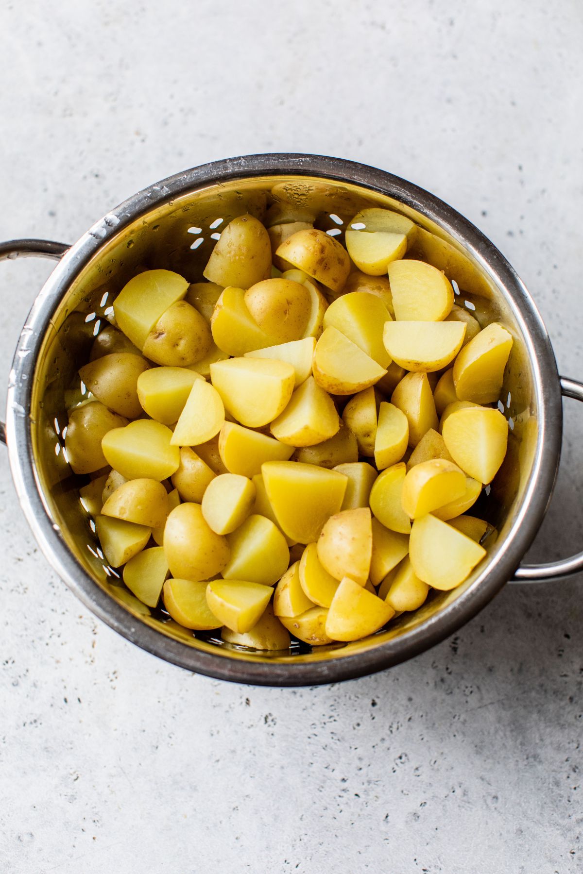 Draining quartered potatoes in a colander.